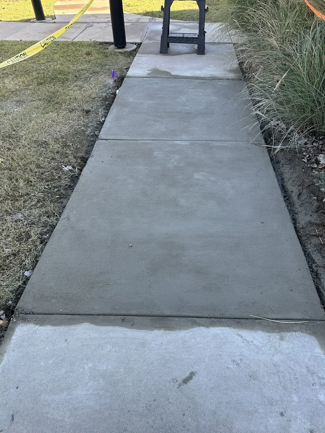 New concrete driveway with a broom finish beside a home